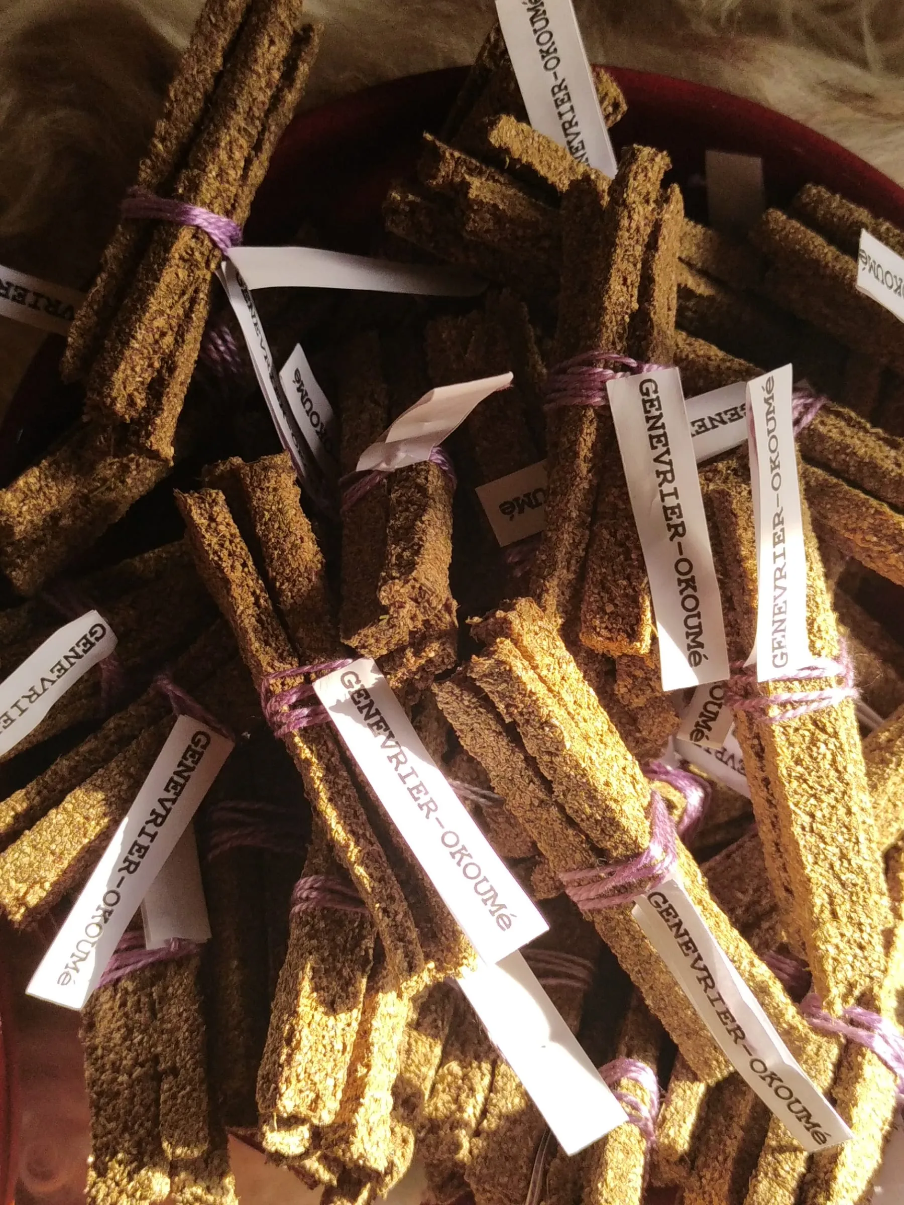 Barrettes d'encens Genévrier – Okoumé liées en fagots par un fil violet, avec leurs étiquettes