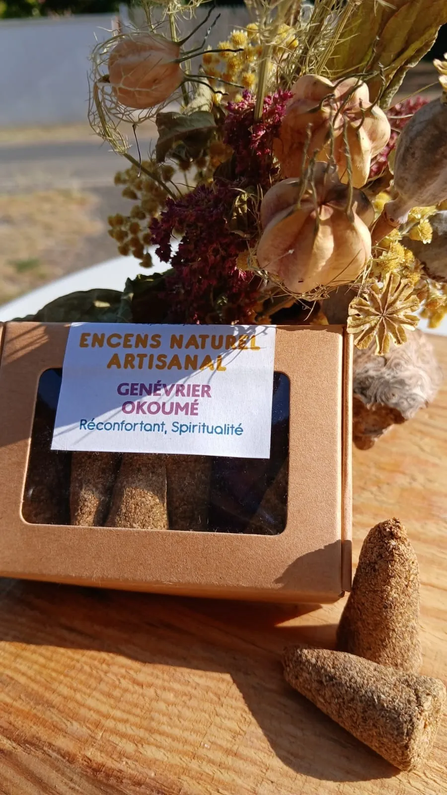 Boîte fenêtre de cônes d'encens Genévrier – Okoumé devant un bouquet de fleurs séchées